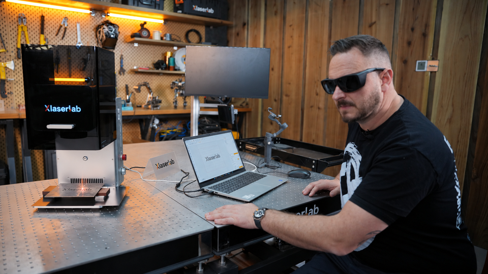 Technician operating Xlaserlab laser marking machine to engrave metal plates