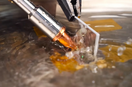 Close-up of an X1 Pro laser welding nozzle working on a metal T-joint submerged in shallow water