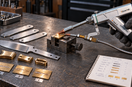 Handheld laser welding a brass sample in a fixture, with knife fittings, labeled test pieces, and a material test log