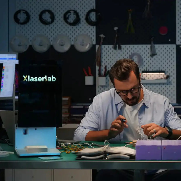 Workers holding engraved products next to the e3 laser engraving machine